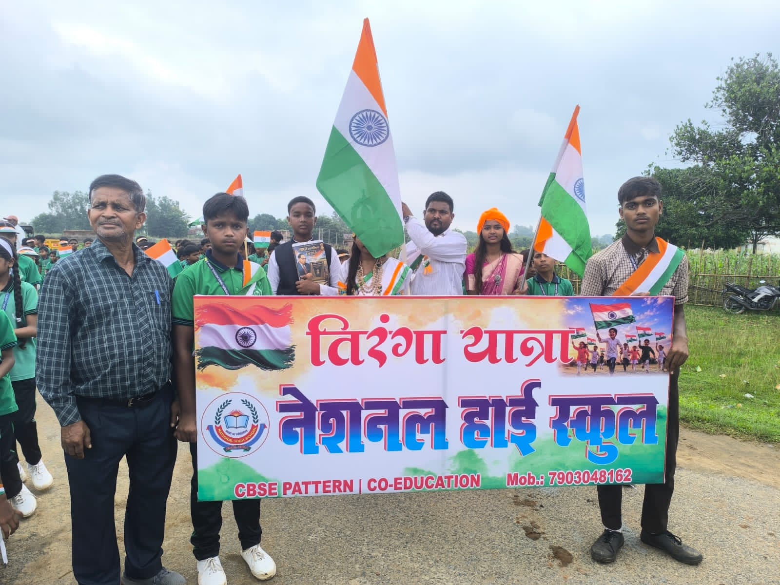 Students of National High School, Bagodar, leading the Independence Day special rally with the school banner and national flag on a village road.